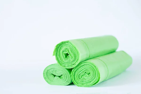 Beyaz arka planda izole edilmiş üç rulo biyolojik çözünebilir plastik yeşil torba. Sıfır atık yaşam tarzı kavramı
