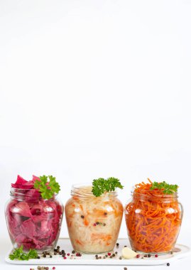 Pickled and fermented homemade vegetables. Sauerkraut, marinated red cabbage and carrot in open glass jars with copy space clipart