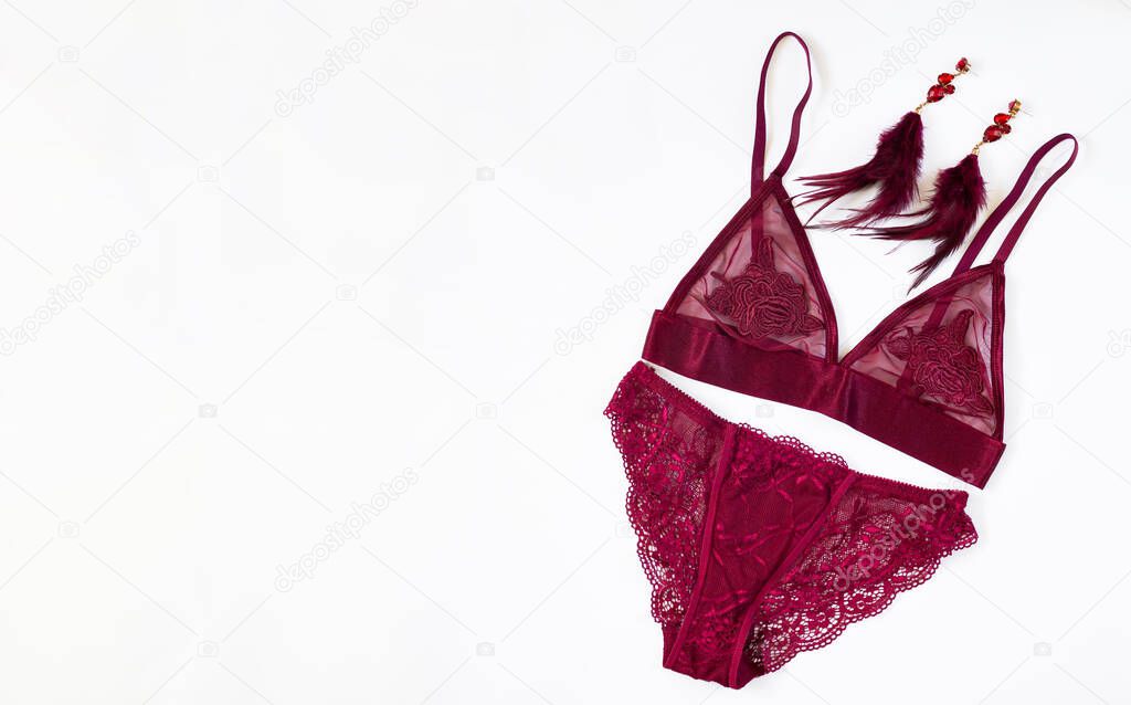 Sexy lace burgundy women's lingerie with fashion earrings isolated on white background. Top view with copy space