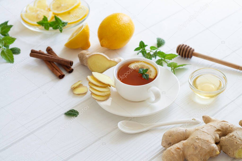 Ingredients for ginger tea with lemon, honey, mint, cinnamon on white table