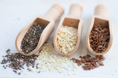 Chia, keten ve beyaz susam tohumlu ahşap kepçeler.