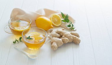 Nane yapraklı ve beyaz ahşap masadaki limonlu sağlıklı zencefil çayı.