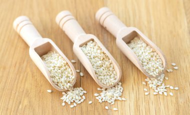 Tahta masadaki beyaz susam tohumlu üst manzara kepçeleri