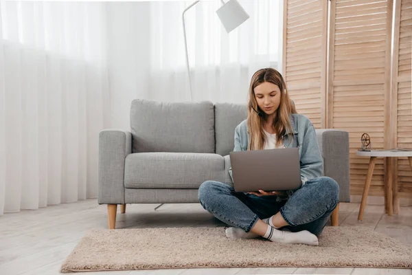 Gülümseyen genç kız kulaklık takıyor ve laptoptan arıyor. Mutlu melez kız öğrenci bilgisayar ekranına bakıyor webinar izliyor ya da webcam 'den görüntülü sohbet yapıyor..