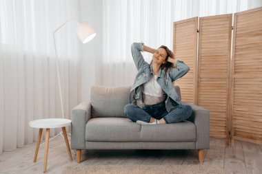 Kot pantolonlu ergen kız Webinar 'dan sonra koltukta oturuyor ve rahatlıyor.