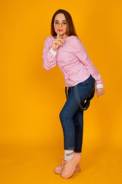 Şık pembe tişörtlü güzel bir kadın sarı arka planda izole edilmiş bir yerde 