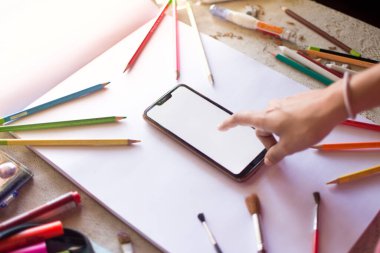 Kalemler ve teknoloji. Cep telefonu beyaz arkaplanlı Parmaklayan Cep Telefonu.