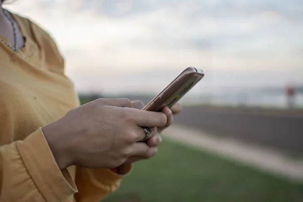 hands holding a cell phone with a landscape in the background