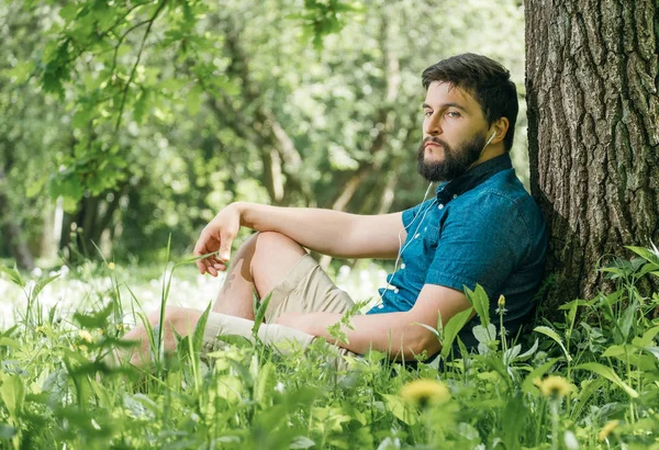 Молодой Человек Слушает Музыку Зеленом Летнем Лесу Расслабляется — стоковое фото
