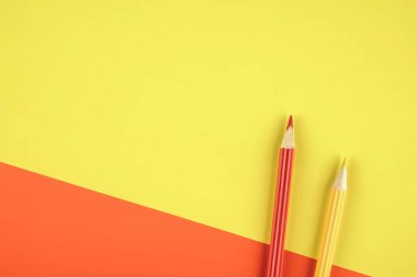 Kırmızı ve sarı renkli kağıt arka plan üzerinde renkli kalemler. Minimalist yaratıcı kavramı