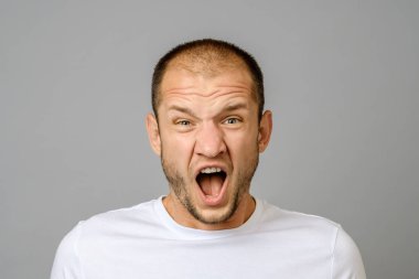 gri arka plan üzerinde çığlık öfkeli genç adam portresi