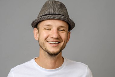 Gülümseyen genç adam portresi. Kameraya bakarak gri arka plan üzerinde yakışıklı genç
