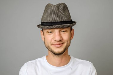 Gülümseyen genç adam portresi. Kameraya bakarak gri arka plan üzerinde yakışıklı genç