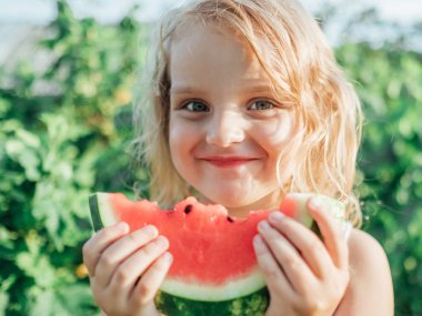Çocuk yemek karpuz açık havada. Çocuklar için sağlıklı snack. Küçük kız bir dilim karpuz kırmızı holding