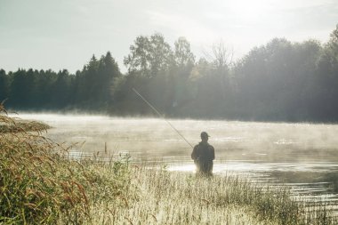 Adil güneş ışığı sabahın erken saatlerinde gündoğumu zaman ile nehrinde Balık tutma adam silüeti