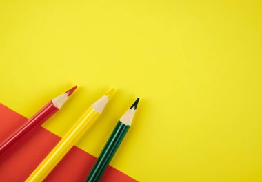 Renkli Kağıt arka plan üzerinde kırmızı, yeşil ve sarı renkli kalemler. Minimalist yaratıcı kavramı