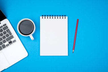 En az işyeri dizüstü bilgisayar ve renkli arka plan üzerinde boş not defteri. Üstten Görünüm. Düz yatıyordu