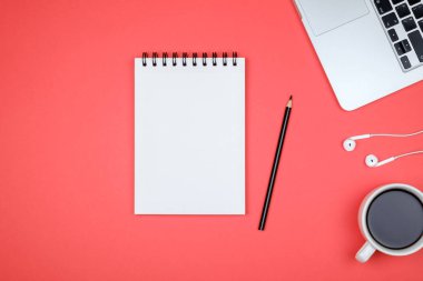 En az işyeri dizüstü bilgisayar ve renkli arka plan üzerinde boş not defteri. Üstten Görünüm. Düz yatıyordu