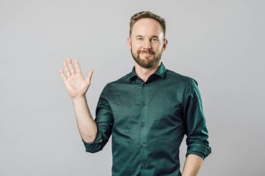 Dost ve mutlu genç sakallı adam gri backgro üzerinde hi söyleyerek