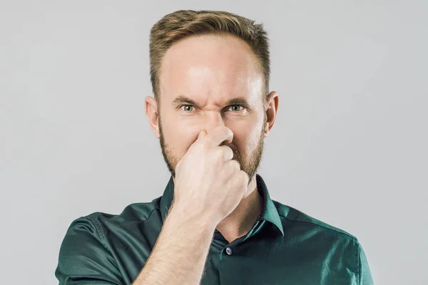 Портрет хлопця, що закриває ніс пальцями на сірому фоні — стокове фото
