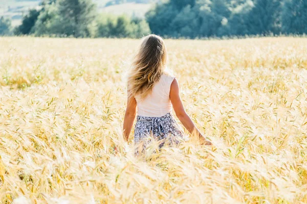 Mulher em um vestido andando ao longo do campo — Fotografia de Stock