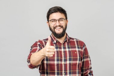 Young man holds his thumb up. Isolated on gray