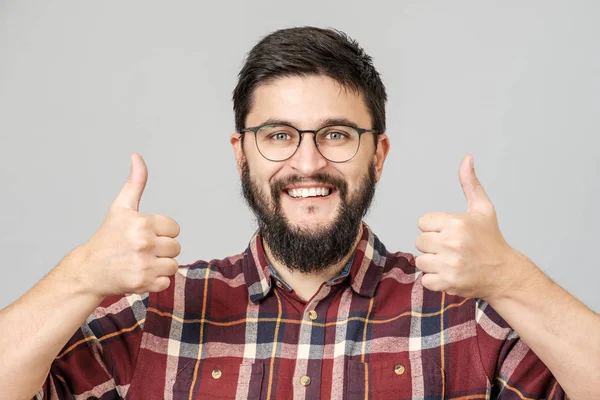 Young man holds his thumb up. Isolated on gray — 스톡 사진