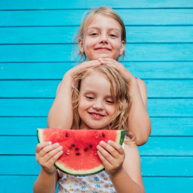 İki küçük kız kardeş ve olgun kırmızı karpuz gülümsüyor.