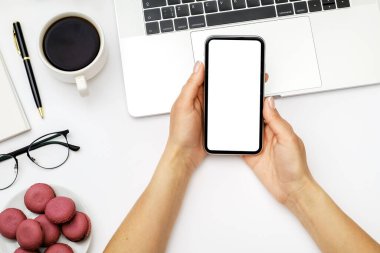 Kadın el ele tutuşmasını ve bilgisayarın arka planında boş ekranlı siyah cep telefonu kullanmasını görüntüle. Üst Manzara. Düz yatıyordu