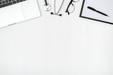 Bilgisayarı ve steteskopu beyaz masada olan modern bir doktorun işyeri. Üst Manzara. Düz yatıyordu