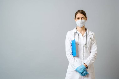 Krizi çözmek için ameliyat maskesi takan mutlu bir doktor. Gri arkaplanda izole