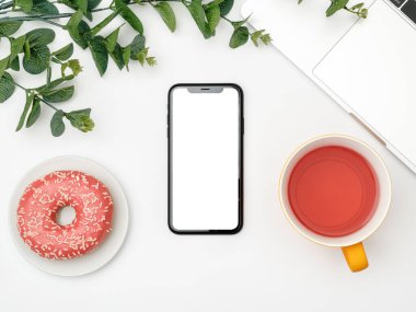 Beyaz ofis masası boş ekranlı akıllı telefon, dizüstü bilgisayar ve malzemeler. Üst görünüm, kopyalama alanı, düz uzanma