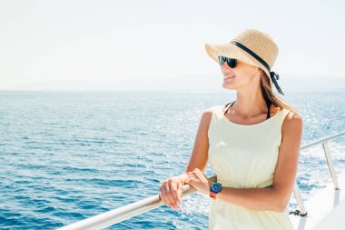 Yaz tatili boyunca teknede gülümseyen genç bir kadın.