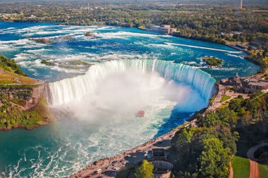 Aerial top landscape view of Niagara Falls and tour boat in water between US and Canada.  Horseshoe of famous Canadian waterfall on sunny day clipart
