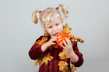 Çok güzel komik beyaz sarışın beyaz kız portre sarı sonbahar yaprakları ile Cadılar Bayramı için giyinmiş. Eğleniyor studio sonbahar mevsim tatil için oynayan çocuk. Küçük oyuncak kabak tutan çocuk