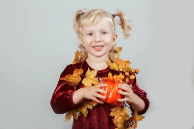Çok güzel komik beyaz sarışın beyaz kız portre sarı sonbahar yaprakları ile Cadılar Bayramı için giyinmiş. Eğleniyor studio sonbahar mevsim tatil için oynayan çocuk. Küçük oyuncak kabak tutan çocuk