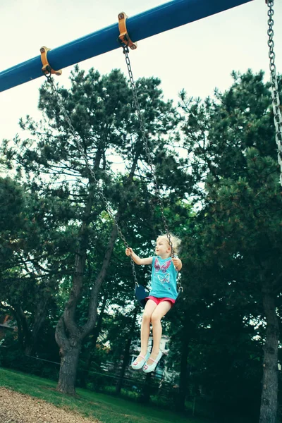 シャツや夏の日の外遊び場スイング ショート パンツに幸せな笑みを浮かべて小さな幼児女の子の肖像画 幸せな子供時代のライフ スタイルのコンセプトです レトロなビンテージ フィルム フィルター トーン — ストック写真