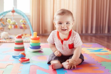 Portre sevimli sevimli sarışın beyaz gülümseyen çocuk çocuk çocuk çocuk odası katta oturan mavi gözlü. Küçük bebek playmat evde oyuncaklar ile oynama. Erken eğitim geliştirme kavramı.