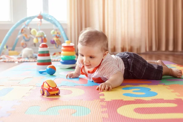 可爱可爱的金发白种人的肖像微笑的男孩与蓝色的眼睛爬行在地板上孩子们的房间 小宝宝在家里玩玩具 Playmat 早期教育发展观 — 图库照片