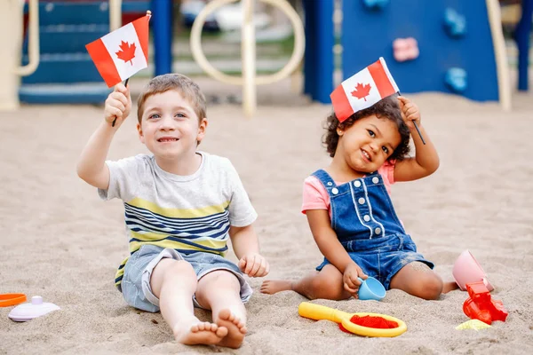 ปภาพของเด กชายน Caucasian และลาต นสาวทารกสเปนถ อโบกธงแคนาดา กหลายเช อชาต ฉลองว นแคนาดา — ภาพถ่ายสต็อก