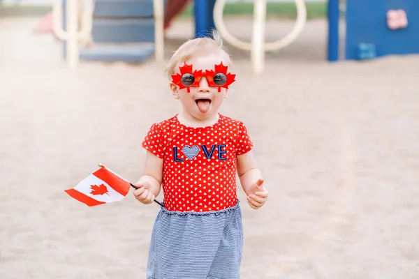 愛らしいかわいい金髪白人赤ちゃん幼児女の子カナダ国旗を持っての肖像画 面白いメープルを身に着けている女児の葉カナダ日を祝うサングラス — ストック写真