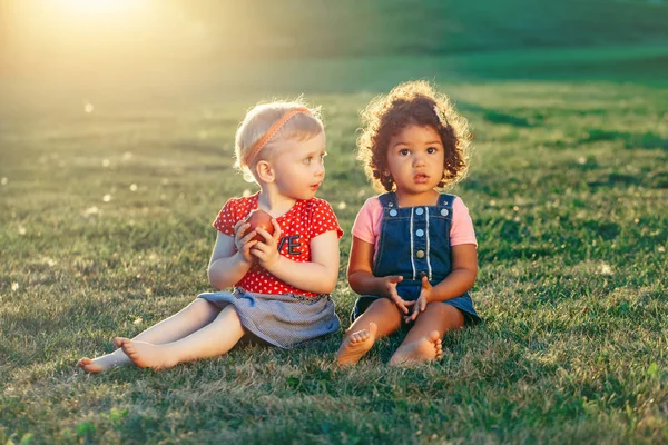 共有のリンゴを一緒に座っている白人およびラテン系の白人のヒスパニック女の子子供のグループの肖像画 つの夏の日の公園で外食べるフルーツを赤します 親友は永遠に 児童の健全です — ストック写真