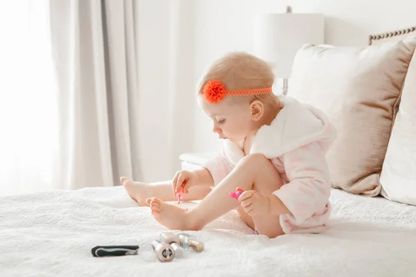可爱的金发白人女孩画指甲坐在家里的床上 女孩子做指甲 幼儿玩使用化妆品 — 图库照片