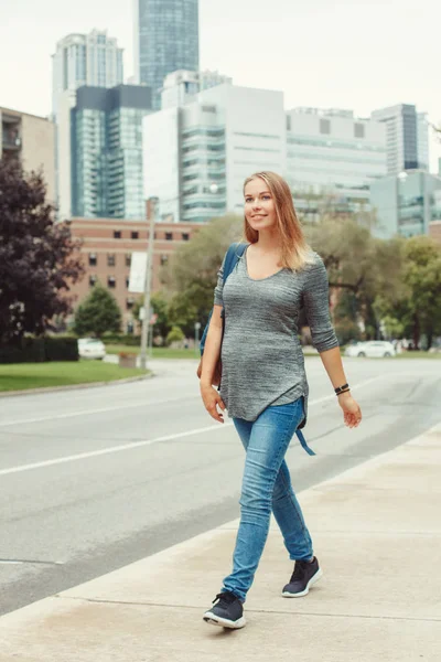 Happy healthy pregnancy. Portrait of caucasian pregnant young blonde Caucasian woman walking  in busy urban city outside. Beautiful slim sporty expecting mom lady.