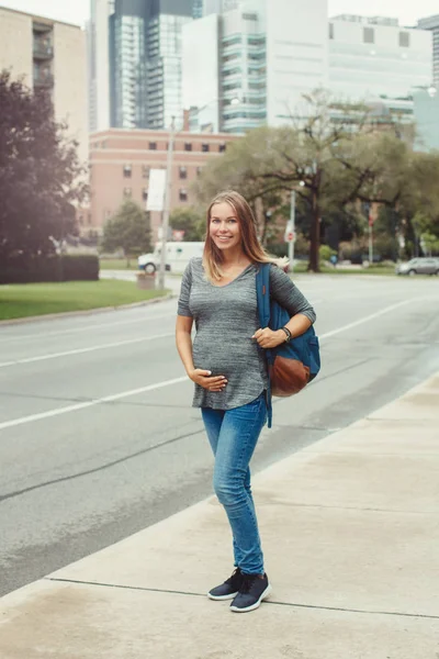 Happy healthy pregnancy. Portrait of caucasian pregnant young blonde Caucasian woman walking  in busy urban city outside. Beautiful slim sporty expecting mom lady.