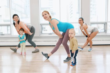 Grup egzersiz dersi için gevşek bebek ağırlığı ile beden eğitimi dersinde işi çocuk olan üç genç kadın. Çocuklara annelerin çocukları küçük çocuklar ile uygunluk. Ana Etkinlik kavramı yaşam tarzı