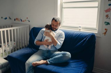 Yeni doğan bebek sakinleştirmeye çalışırken orta yaş beyaz baba portresi. Erkek üst ellerinin üstünde tutarak. Otantik yaşam tarzı documenatry an. Bekar Baba aile hayatı kavramı. 