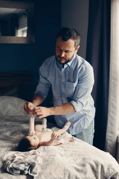 Middle age Caucasian father changing diaper for newborn baby daughter. Male man parent taking care of child at home alone. Authentic lifestyle candid moment. Single dad family life concept.