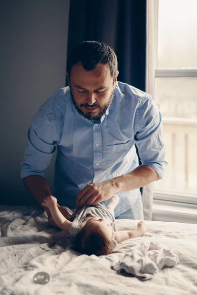 Middle age Caucasian father changing diaper for newborn baby daughter. Male man parent taking care of child at home alone. Authentic lifestyle candid moment. Single dad family life concept.