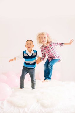 Grup portresi yatak yatak üzerinde atlama iki mutlu beyaz beyaz sevimli sevimli komik çocuk. Erkek ve kız birlikte eğleniyor. Sonsuza kadar en iyi arkadaş. 